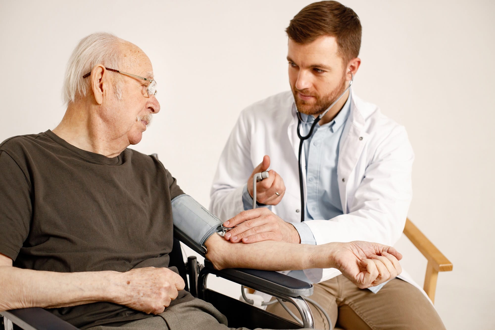 Male doctor and old man on a wheelchair isolated on a white back