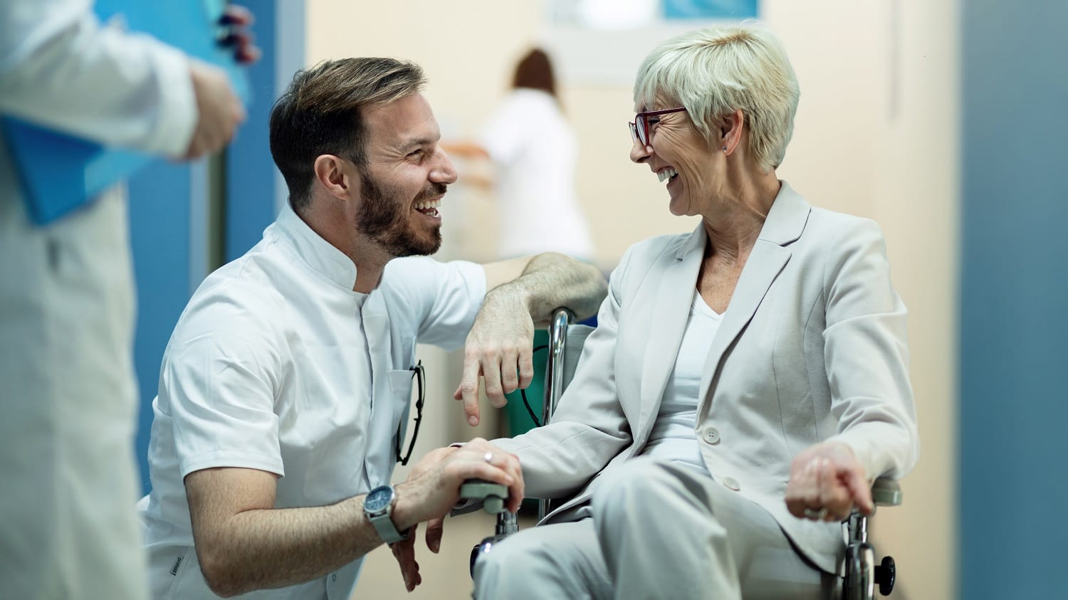 Happy senior woman in wheelchair talking to a doctor in a hospital.