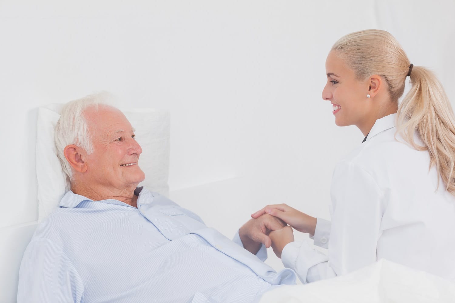Doctor comforting elderly patient in bed